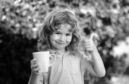 Téléchargez les photos : Portrait mignon d'enfants avec tasse, enfant tenant une grande tasse avec tisane. Bonne enfance - en image libre de droit
