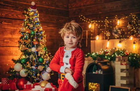 Foto de Niño con calcetines navideños sobre fondo de madera. Feliz niño sonriente con calcetines de regalo de Navidad. Niño feliz divirtiéndose con el regalo - Imagen libre de derechos