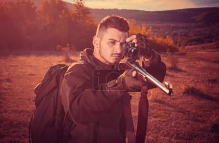 Photo for Calibers of hunting rifles. Rifle Hunter Silhouetted in Beautiful Sunset. Autumn. Hunter with Powerful Rifle with Scope Spotting Animals - Royalty Free Image
