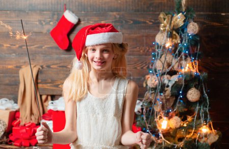 Photo for Kid having fun near Christmas tree indoors. Children gift. Christmas card. Portrait of happy Little girl looking at decorative toy ball by Christmas tree - Royalty Free Image