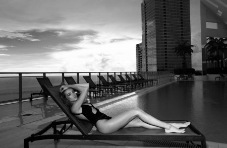 Téléchargez les photos : Femme sexy sur un transat près de la piscine. Femme sensuelle relaxant dans la piscine spa - en image libre de droit