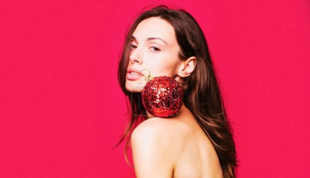 Photo for Young beautiful girl with christmas ball. Close up photo of sexy lady isolated over red background - Royalty Free Image