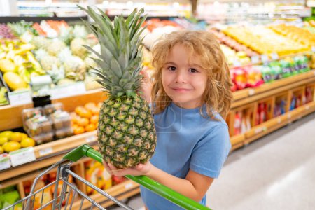 Foto de Un chico de compras. Niño con cesta llena de verduras y frutas. Un chico en una tienda de comida. Concepto de supermercado de compras y supermercados. Niño con cesta de la compra - Imagen libre de derechos