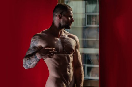 Photo for Sensual muscular hunk in room on window curtains. Muscular shirtless man model in bedroom. Gay sexy muscular model. Strong shoulders and chest. Muscular sexy man with naked torso. Athletic body - Royalty Free Image