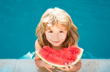 Téléchargez les photos : Enfant mangeant pastèque près de la piscine pendant les vacances d'été. Les enfants mangent des fruits à l'extérieur. Aliments sains pour les enfants. Petit garçon jouant dans la piscine avec une tranche de melon d'eau - en image libre de droit