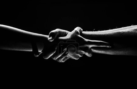 Photo for Hands gesturing on black background. Giving a helping hand. Support and help, salvation. Strength strong hads of two people at the time of rescue. Helping hand outstretched for salvation. Strong hold - Royalty Free Image