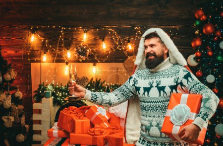Téléchargez les photos : Homme de Noël en chapeau de Père Noël. Pull barbu moderne santa claus en tricot. Nouvel an concept de Noël. Nouvelle fête de l'année - en image libre de droit