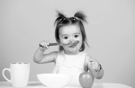 Photo for Babies eating, healthy food for a baby. Kid eating healthy food with a spoon at studio, isolated. Funny kids face - Royalty Free Image