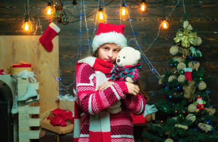 Téléchargez les photos : Adolescent de Noël. Il s'amuse près du sapin de Noël à l'intérieur. Cadeau d'enfants. Les enfants de Noël. Décoration d'arbre de Noël. Enfants d'hiver - en image libre de droit