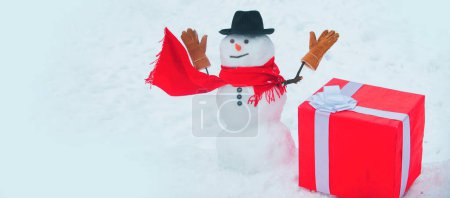Foto de Muñeco de nieve con gran regalo. Feliz Navidad y feliz año nuevo tarjeta de felicitación. Tarjeta de felicitación de arte festivo con muñecos de nieve. Gift presenta el concepto. Regalo de muñeco de nieve. Regalos de entrega y emociones de regalo - Imagen libre de derechos
