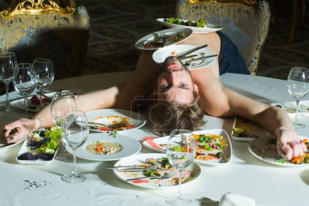 Photo for Hungry Funny man having binge eating in the restaurant. Very hungry guy. Diet concept. Taste food for Hungry Sexy Man. Meals that cater to every taste. Delicious Meal. Hungry Sexy Man - Royalty Free Image