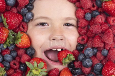 Téléchargez les photos : Fruit Berry, les enfants font face à des fruits. Des fruits drôles. Les enfants font face avec des baies mélange de fraise, myrtille, framboise, mûre. Fruits drôles - en image libre de droit