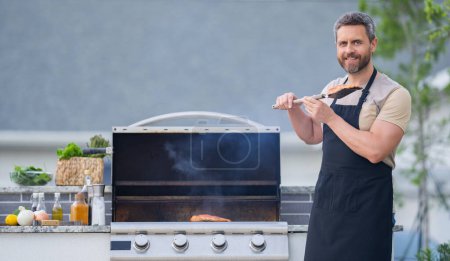 Photo for Man cooking tasty food on barbecue grill outdoors. Man cooking barbecue grill at backyard. Chef preparing food on barbecue. Millennial man grilling meat on barbecue grill. Bbq party. Meal grilling - Royalty Free Image