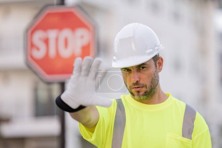 Photo for Builder with stop road sign. Builder with stop gesture, no hand, dangerous on building concept. Man in worker uniform and hardhat with open hand doing stop sign - Royalty Free Image