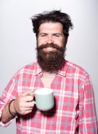 Téléchargez les photos : Bonne matinée. Un homme souriant tient une tasse de café. Thé du matin. Bonjour. Bonjour. Un homme heureux avec une tasse de thé. Homme hippie avec une tasse de café. Homme barbu souriant tenir tasse de thé. Réveille-toi. Bonne journée. Thé du matin - en image libre de droit