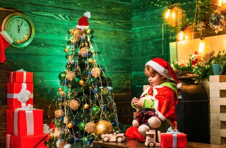 Téléchargez les photos : Fête de la famille Noël. Cadeaux et surprises. Mignon petit garçon enfant jouer près de l'arbre de Noël. Joyeux Noël et bonne année. Les enfants apprécient les vacances d'hiver à la maison. Maison remplie de joie et d'amour
. - en image libre de droit