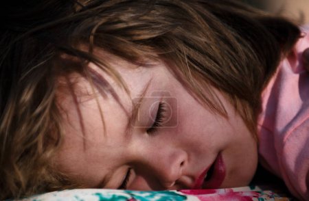 Foto de Cara de primer plano del niño acostado en la cama y durmiendo. El niño duerme tranquilamente en la cama en casa. Adorable lindo niño o bebé dulce soñando en el dormitorio. Un niño encantador duerme profundamente y relájate. - Imagen libre de derechos