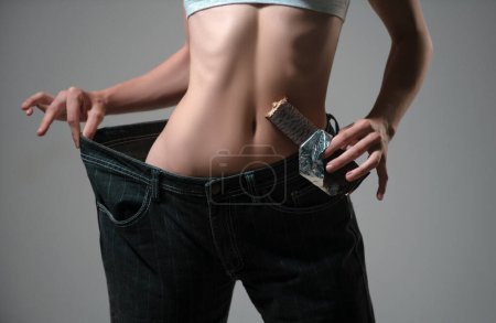 Photo for Slim waist. Diet food, chocolate dieting. Woman showing weight lost. Slim girl wearing oversized pants. Woman shows weight loss. Dieting. Woman showing slim body, healthy eating - Royalty Free Image