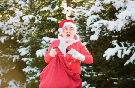 Foto de Funny Santa con regalo en Nochebuena afuera. Tarjeta postal, tarjeta de felicitación - Imagen libre de derechos