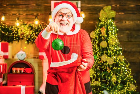 Téléchargez les photos : Joyeux Père Noël habillé en vêtements d'hiver pensez à Noël près de l'arbre de Noël. Thème Vacances de Noël et nouvel an hiver - en image libre de droit