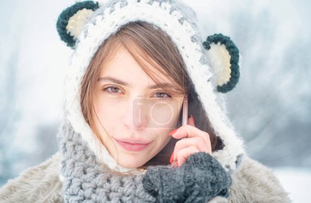 Photo for Portrait of a young woman in snow. Winter woman using mobile phone or smartphone. Happy girl winter portrait with smartphone - Royalty Free Image