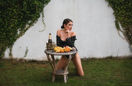 Foto de Young sexy woman relaxing and eating fruit outdoor. Exotic summer diet, tropical fruits. Beautiful romantic young woman posing sexy outdoor. Spring and summer. Natural female beauty - Imagen libre de derechos