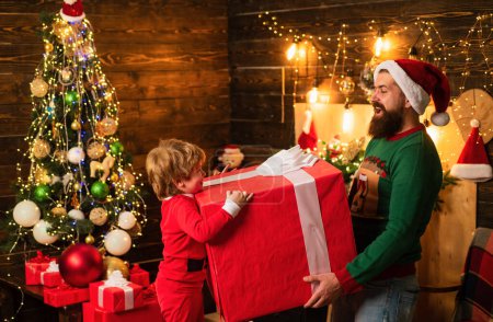 Foto de Lindo niño pequeño con los padres está decorando el árbol de Navidad en el interior. Ambiente navideño casero. Niños de Navidad con emoción de regalo - concepto de felicidad - Imagen libre de derechos