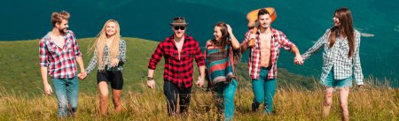 Foto de Group people in a hike through the mountains. Friends on a camping trip walking. Happy friends walking on mountain. Friends spring travel vacation banner. Friendship holiday concept - Imagen libre de derechos