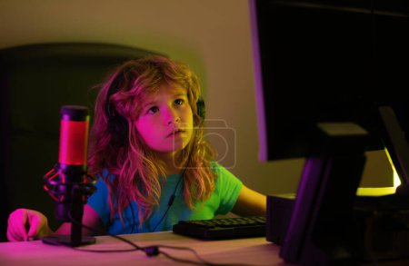 Foto de Cute preschool child watching video lesson by laptop. Child using computer technology in home. Kids online working, gaming on a desktop computer pc - Imagen libre de derechos