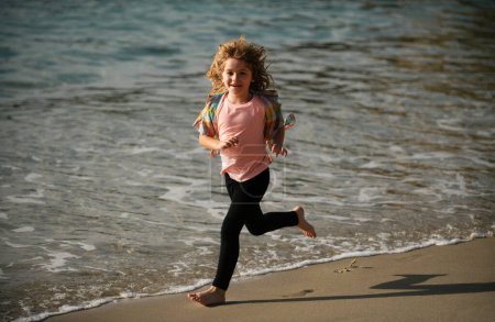 Foto de Niño corriendo a través del agua cerca de la orilla a lo largo de la playa. Un niño corre a lo largo de la costa. Resto de niños en vacaciones de verano. Pequeño atleta en entrenamiento. Ejercicio de corredor, correr para niños - Imagen libre de derechos