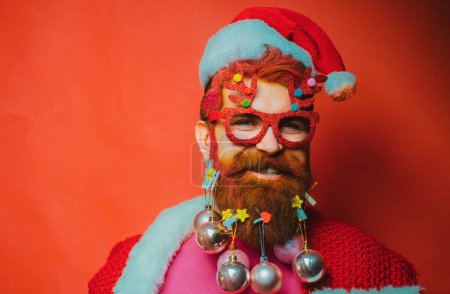 Téléchargez les photos : Les gens de Noël célèbrent le Nouvel An. Barbe moderne Père Noël à Noël Portrait d'un Père Noël sur fond rouge isolé - en image libre de droit