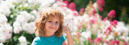 Foto de Banner con retrato de niños de primavera. Lindo niño riega las plantas en el jardín del patio trasero con regadera. Pulgares arriba - Imagen libre de derechos