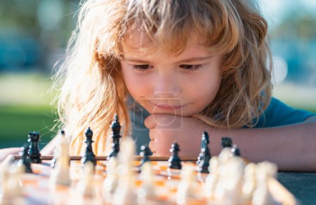 Téléchargez les photos : Chess strategy. Close up face of clever smart child. Kid playing chess - en image libre de droit