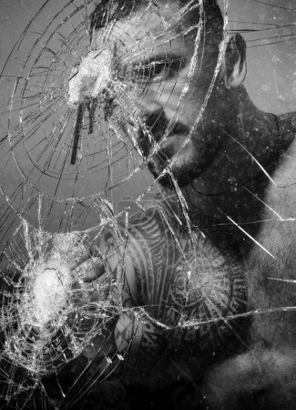 Photo for Aggression. crush test. theft. emotional discharge. bullet hole in glass. broken glass because of hit. macho man behind crushed glass. sexy hispanic man broken mirror. anger aggression. destruction. - Royalty Free Image