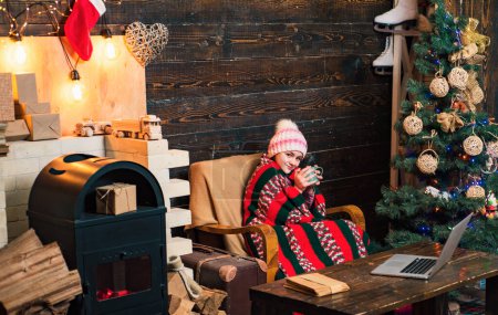 Téléchargez les photos : Heureuse petite fille habillée en hiver vêtements pensez Santa près de sapin de Noël. Happy Kids souriants avec cadeau. Cadeau enfants sur les fêtes de Noël. Enfants d’hiver - en image libre de droit