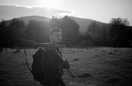 Photo for Rifle Hunter Silhouetted in Beautiful Sunset. Autumn hunting season. Autunm hunting - Royalty Free Image