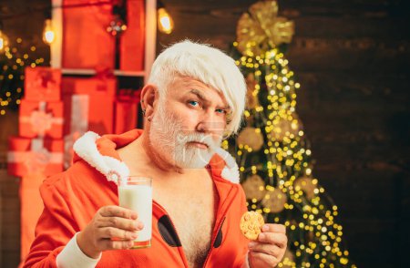 Téléchargez les photos : Noël. Le Père Noël aime les biscuits et le lait laissés pour lui la veille de Noël. Père Noël manger des biscuits et boire du lait la veille de Noël - en image libre de droit