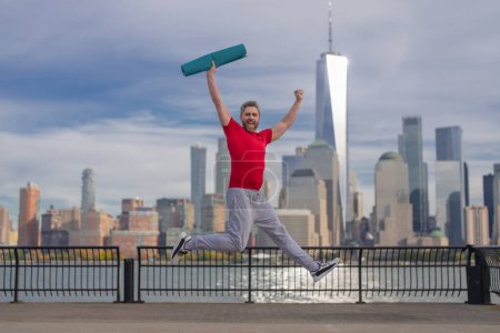 Photo for Mature sportsman outdoor workout, man enjoying active lifestyle outside in NYC. Man doing stretching exercise, preparing for workout near Manhattan. Sporty athletic fit man 40s wear sports clothes - Royalty Free Image