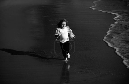 Foto de Niños corriendo al aire libre. Carrera y deporte saludable para los niños. Niño corriendo en el mar de verano, los niños fitness. Carrera y deporte saludable para los niños - Imagen libre de derechos