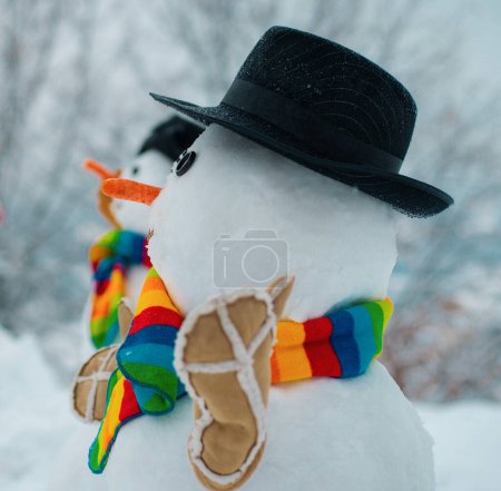 Téléchargez les photos : Bonhomme de neige heureux debout dans le paysage de Noël d'hiver. Le bonhomme de neige porte un chapeau et une écharpe en fourrure. Joyeux Noël et bonne année - en image libre de droit
