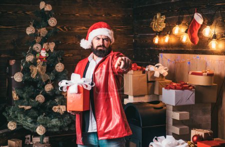 Téléchargez les photos : Santa Claus avec boîte cadeau de Noël rouge. Barbu moderne santa souhaite Joyeux Noël et Bonne année - en image libre de droit