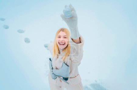 Foto de Hermosa mujer joven en invierno. Mujer rubia joven en suéter y sombrero divertido sosteniendo patines blancos sobre el hombro en el frío día de invierno - Imagen libre de derechos