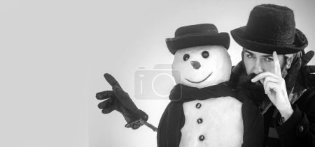 Téléchargez les photos : Joyeux Noël et bonne année. Drôle hiver bonhomme de neige en chapeau jouer avec bonhomme de neige en plein air. Homme avec bonhomme de neige sur fond d'hiver extérieur. Bonhomme de neige pour bannière d'hiver - en image libre de droit