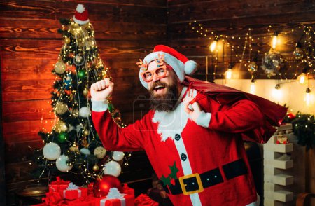 Téléchargez les photos : Père Noël posant sur fond de bois vintage. Les gens de Noël célèbrent le Nouvel An. Père Noël souhaite Joyeux Noël et Bonne année - en image libre de droit
