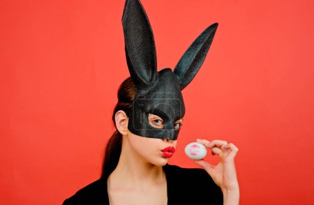 Photo for Easter woman. Woman rabbit, easter bunny girl. Red lip imprint on easter egg on red background. Female mouth kiss. Print of red lips on white egg - Royalty Free Image