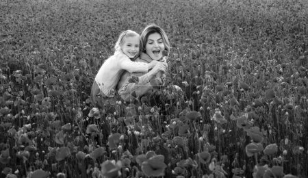 Téléchargez les photos : Belle mère et fille dans le champ de fleurs de pavot de printemps. Maman tient sa fille enfant dans le pré à fleurs balade en dos de porc. Bonne maternité - en image libre de droit