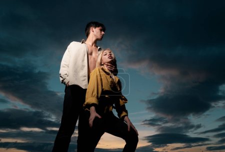 Foto de Retrato sensual de pareja joven enamorada. Pareja cariñosa abrazándose y besándose en el cielo dramático - Imagen libre de derechos