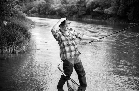 Téléchargez les photos : Homme pêcheur sénior excité avec canne à pêche, bobine de filage sur la rivière. Vieil homme attrapant du poisson, tirant la canne tout en pêchant sur le lac - en image libre de droit