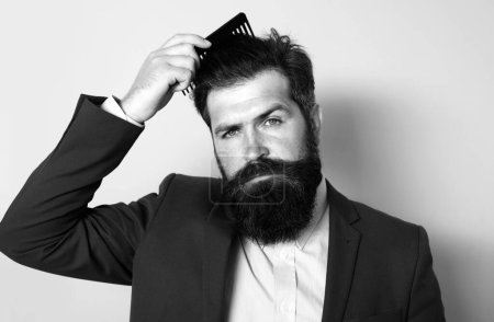 Téléchargez les photos : Man hairstyle, modern haircut. Man styling his hair with a comb. Bearded man with beard, bearded gay. Barbershop concept. Mustache men - en image libre de droit