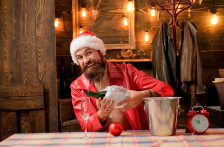 Photo for Happy smiling bearded Santa Claus pushes champagne down in glass. Merry Christmas and Happy Holidays. Amazing Christmas decorated background and lights. Christmas time concept - Royalty Free Image